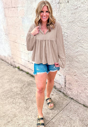 Beige textured gathered yoke collar blouse with long sleeves and a babydoll cut.