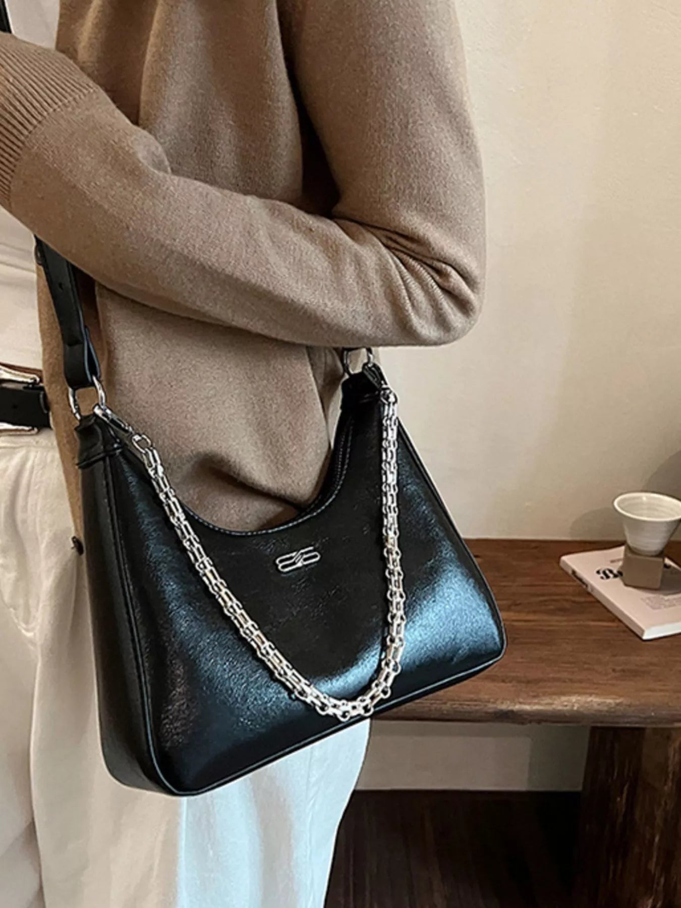 Black patent leather crossbody bag with silver chain detail and logo