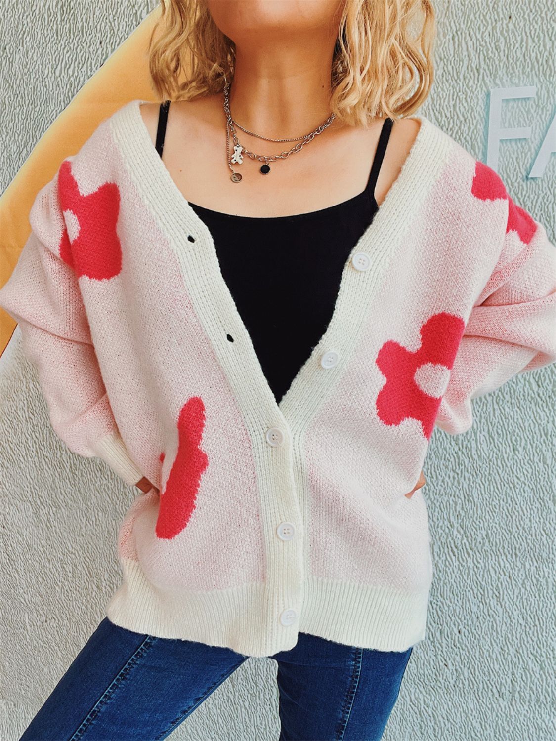 Blush pink acrylic cardigan with playful red floral appliqué, button front, and cream trim.