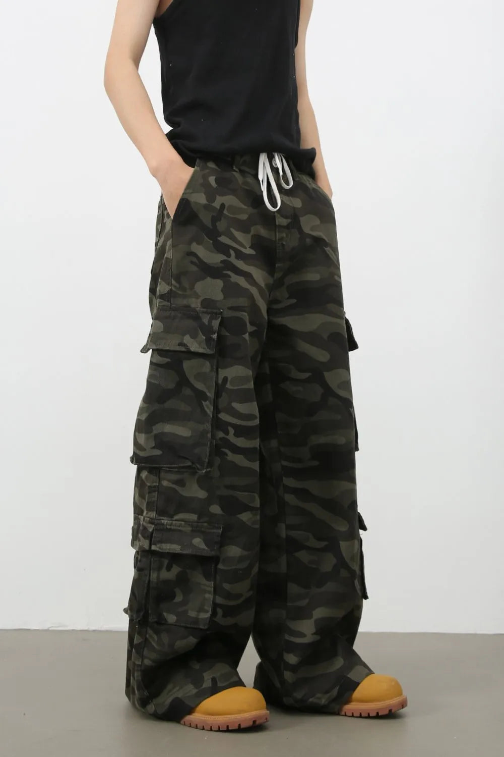 Wide-leg camo cargo pants in black with drawstring waist and multiple pockets.