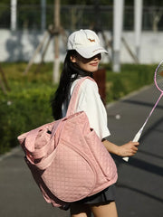 Pink quilted sports racket backpack with diamond pattern and zip pockets.