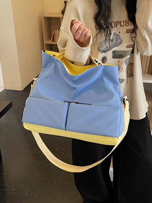 Blue and yellow Oxford cloth travel bag with two front pockets and a crossbody strap.