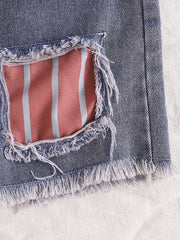 Distressed denim shorts with pink and blue striped lining and frayed hem.