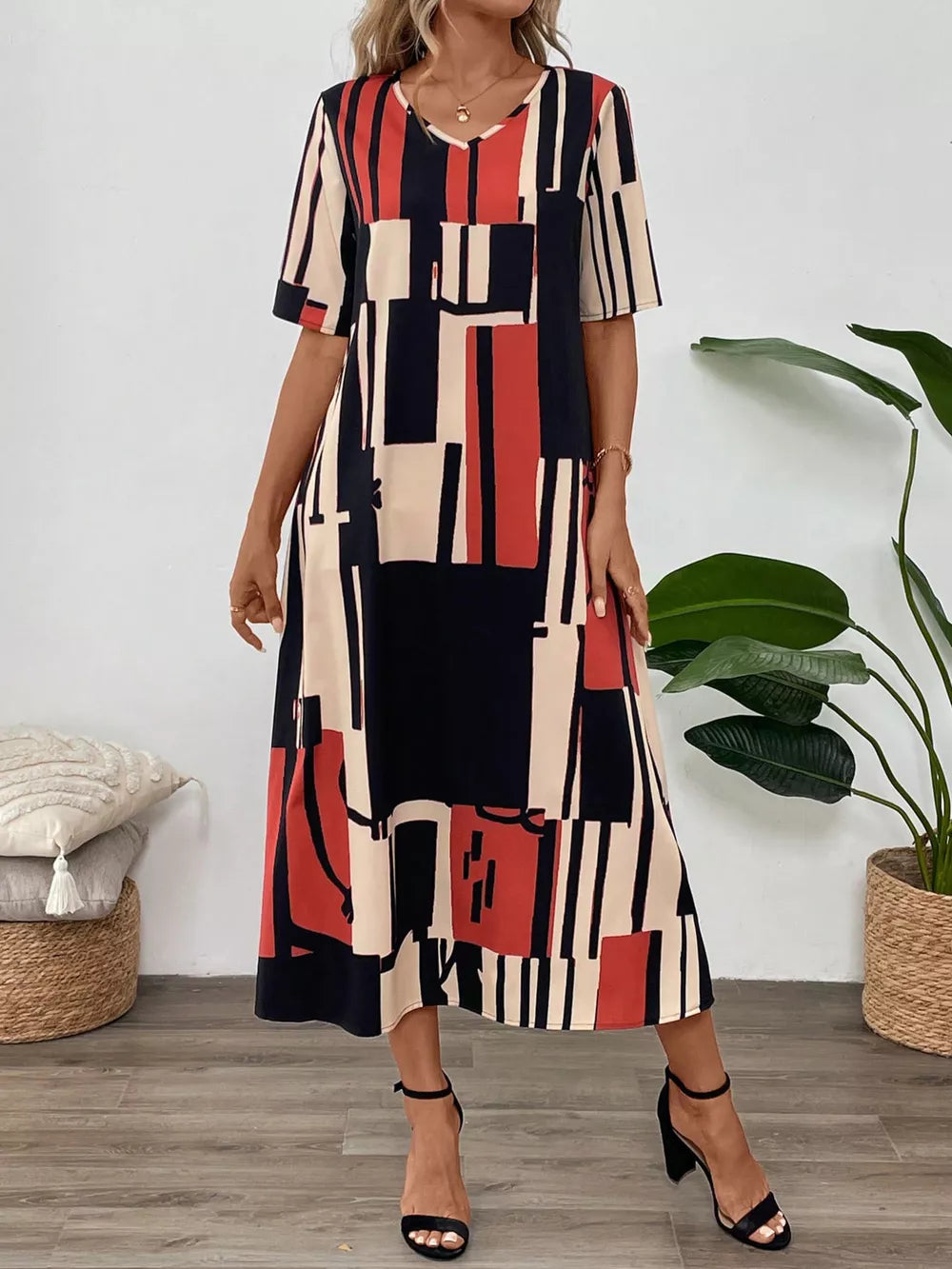 Geometric V-neck midi dress in dark blue, red, and cream abstract print.