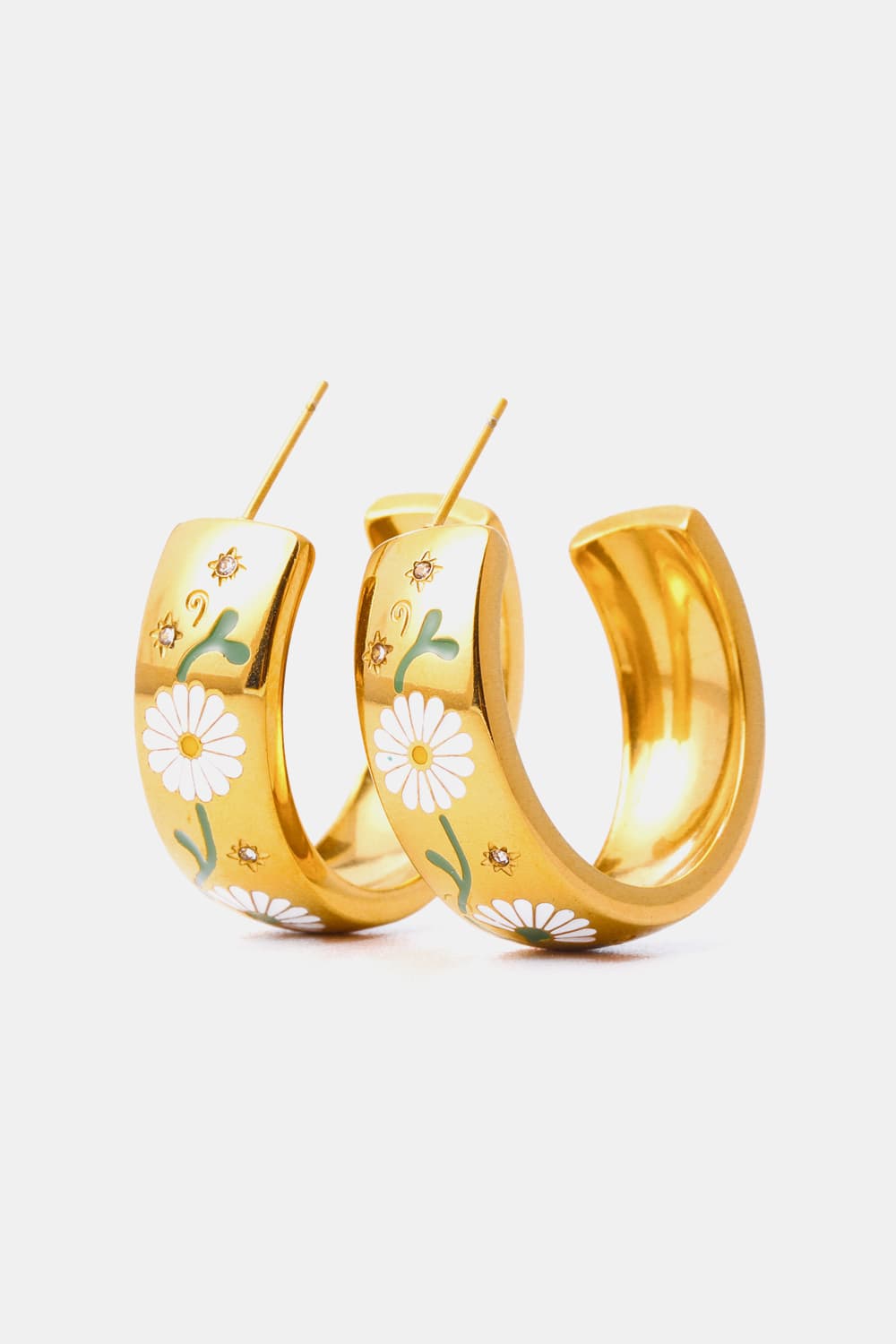 Gold hoop earrings with white daisy enamel detail and small crystal accents.