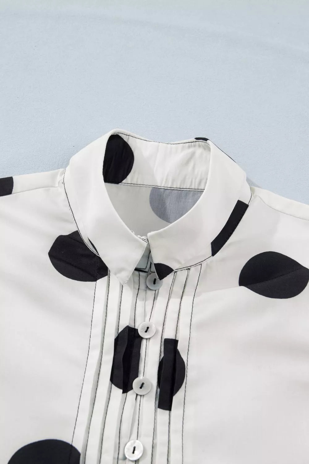 White polka dot dress with collared neckline and button-down front with pintuck details.