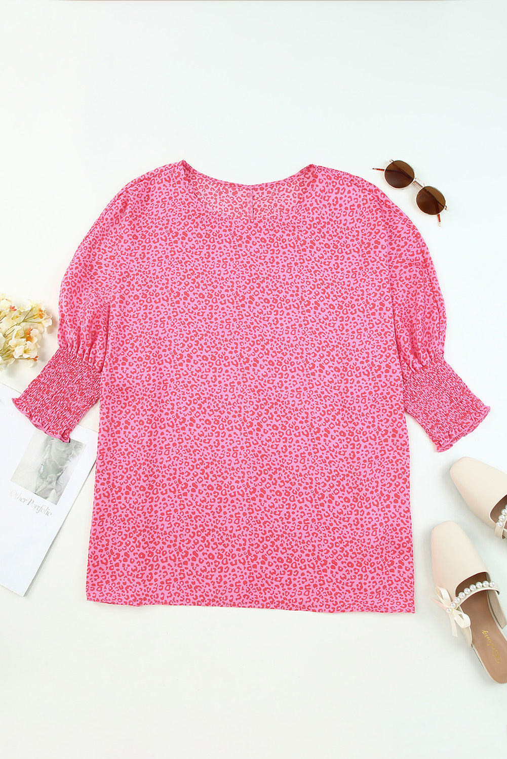 Pink leopard print blouse with smocked sleeves and a round neckline.
