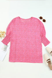 Pink leopard print blouse with smocked sleeves and a round neckline.