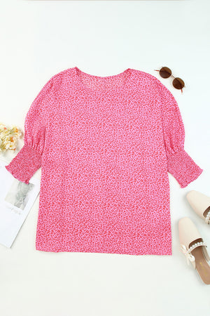 Pink leopard print blouse with smocked sleeves and a round neckline.