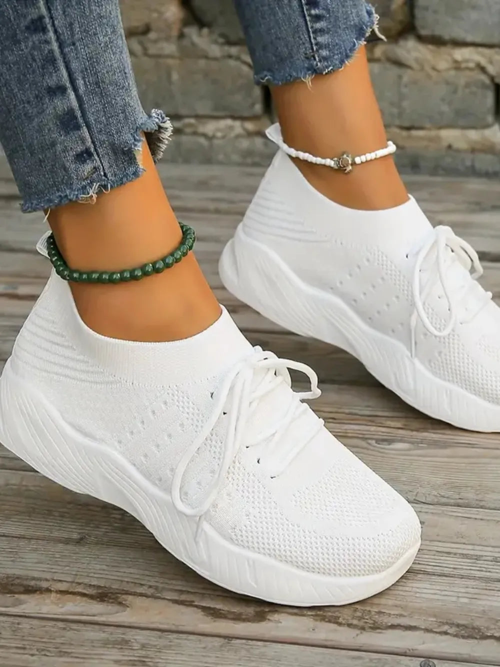 White knit runner sneakers with sculpted sole and white laces.