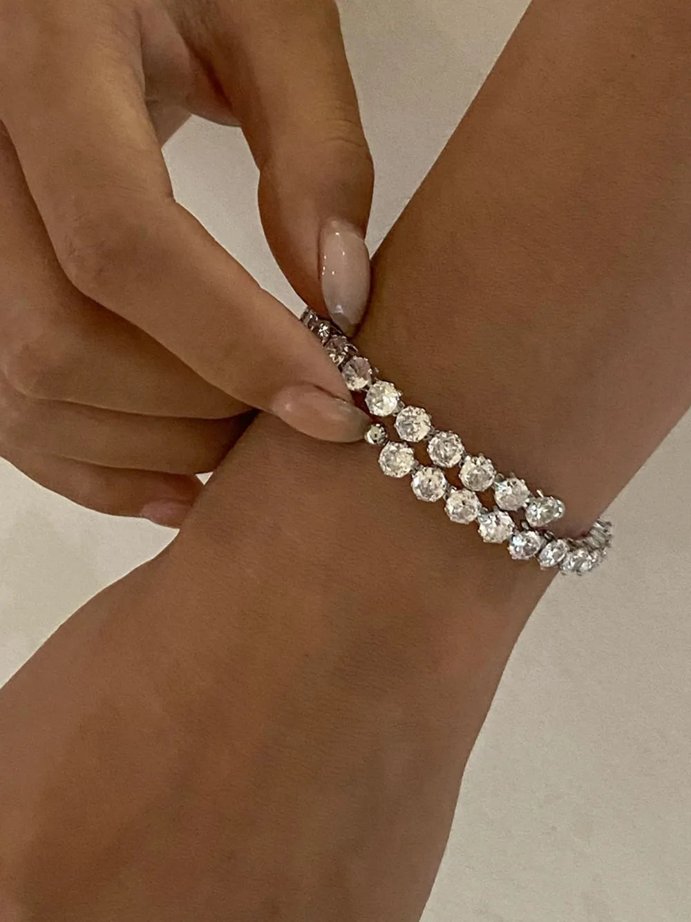 Silver double row pavé bangle bracelet with clear stones on a wrist.