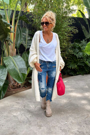 White knit maxi cardigan with balloon sleeves, worn open over a white tank top and distressed jeans.