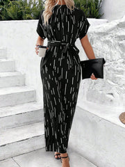 Black wide-leg jumpsuit with raindrop print, tie waist, and short sleeves.