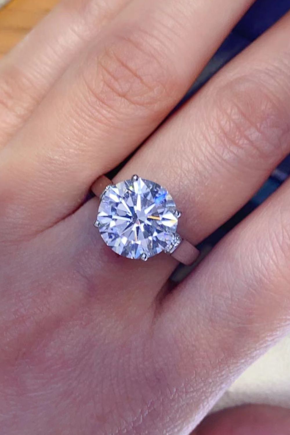 Silver ring with large radiant moissanite solitaire and pavé shoulder details.