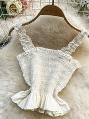 White ruffled crop top with smocked bodice and eyelet trim.