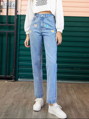 Light wash denim jeans with colorful heart patches and a straight leg cut.