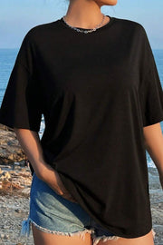 Black oversized graphic tee with crew neck and short sleeves, styled with denim shorts.