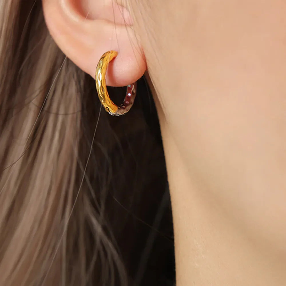 Textured gold huggie hoop earrings with a two-tone finish and hammered detail.
