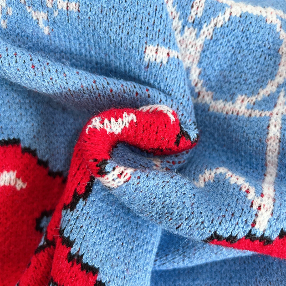 GeoPrint cozy long sleeve knit sweater in blue with red and white geometric pattern detail.