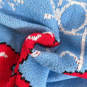 GeoPrint cozy long sleeve knit sweater in blue with red and white geometric pattern detail.