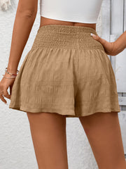 Khaki smocked waist drawstring shorts with textured fabric and a flared hem.
