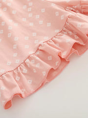 Pink cotton tee with white floral print and ruffled hem detail.