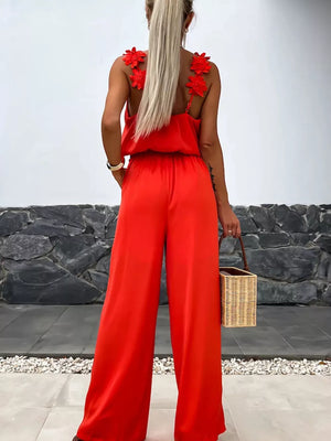 Red floral applique wide-leg jumpsuit with blouson waist and spaghetti straps.