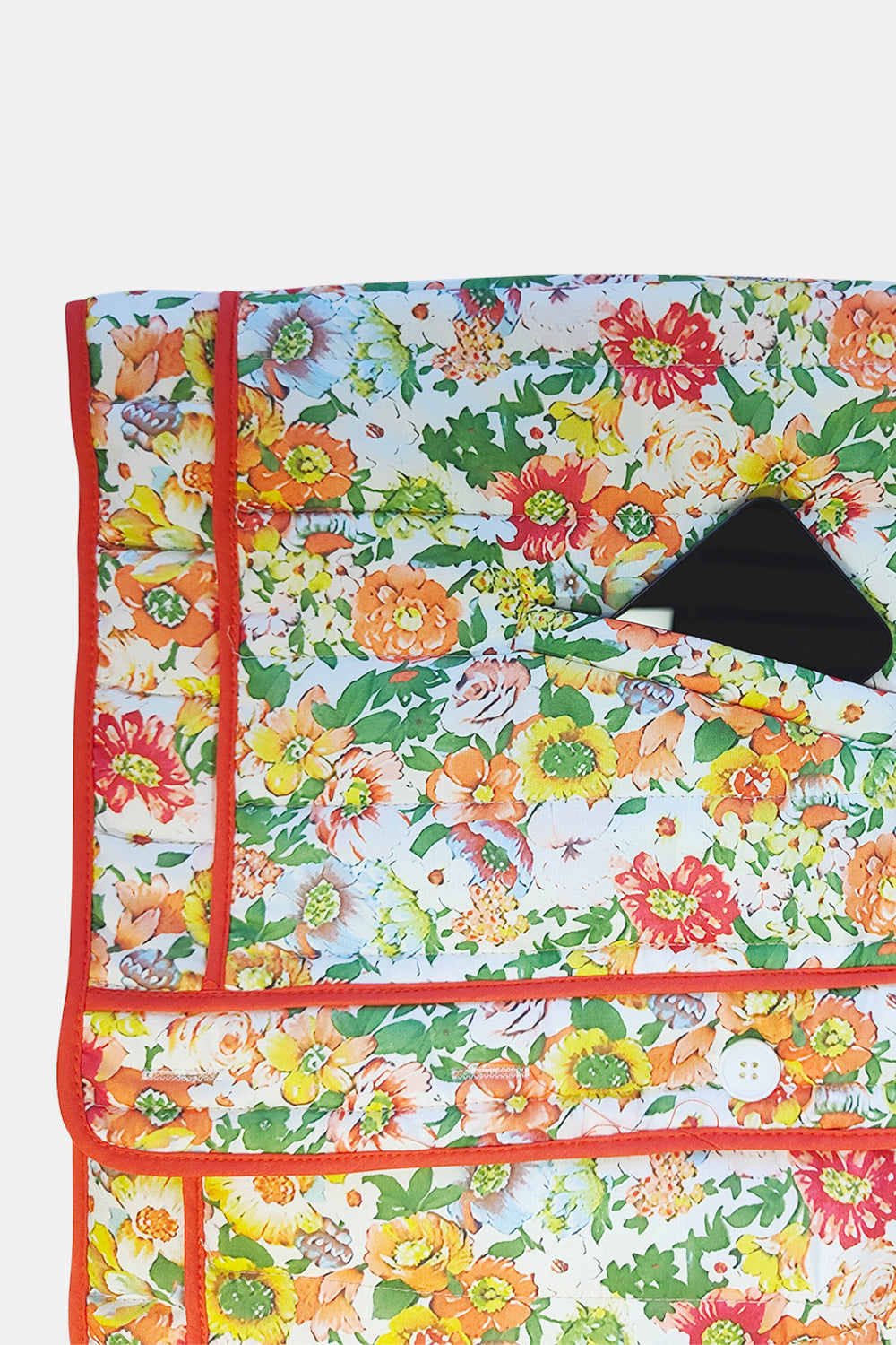 Floral quilted jacket with contrast piping and a pocket holding a phone.