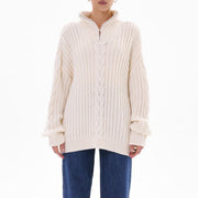 White cable knit zip-neck sweater with ribbed texture and a funnel collar.