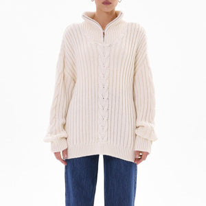 White cable knit zip-neck sweater with ribbed texture and a funnel collar.