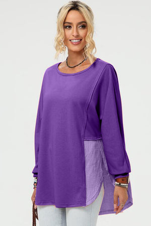 Purple sweatshirt with split panel and asymmetric hemline, featuring a textured fabric insert.