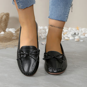 Black slip-on loafers with bow detail and stitched trim.