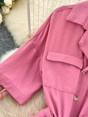 Pink belted wide-leg maternity jumpsuit with buttoned chest pockets and short sleeves.