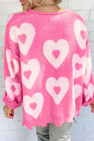 Fuchsia pink knit sweater with white heart motif and pearl embellishments on sleeves.