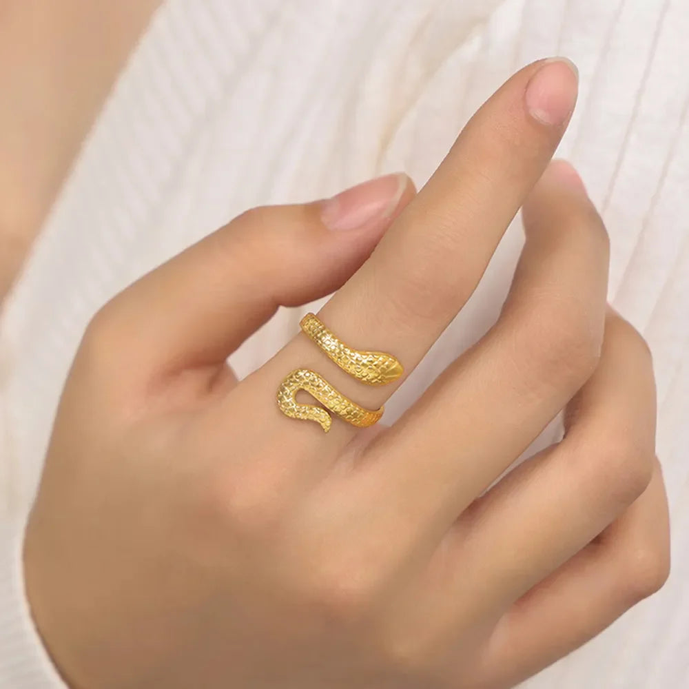 Gold serpent wrap ring with textured scales, worn on a finger.