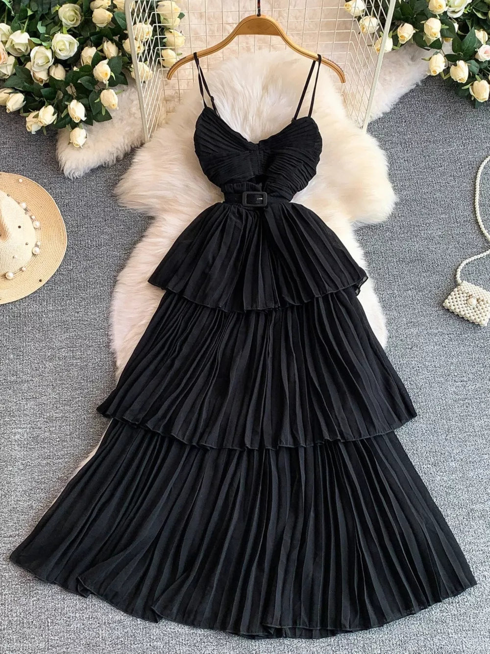Black belted midi dress with spaghetti straps, tiered pleated skirt and buckle detail.