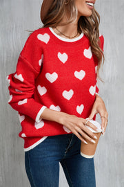 Red acrylic crewneck sweater with white heart intarsia pattern and white trim.