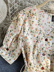 Apricot floral v-neck midi dress with button details and belted waist.