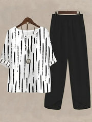 White half sleeve top with black vertical brushstroke print and black pants.