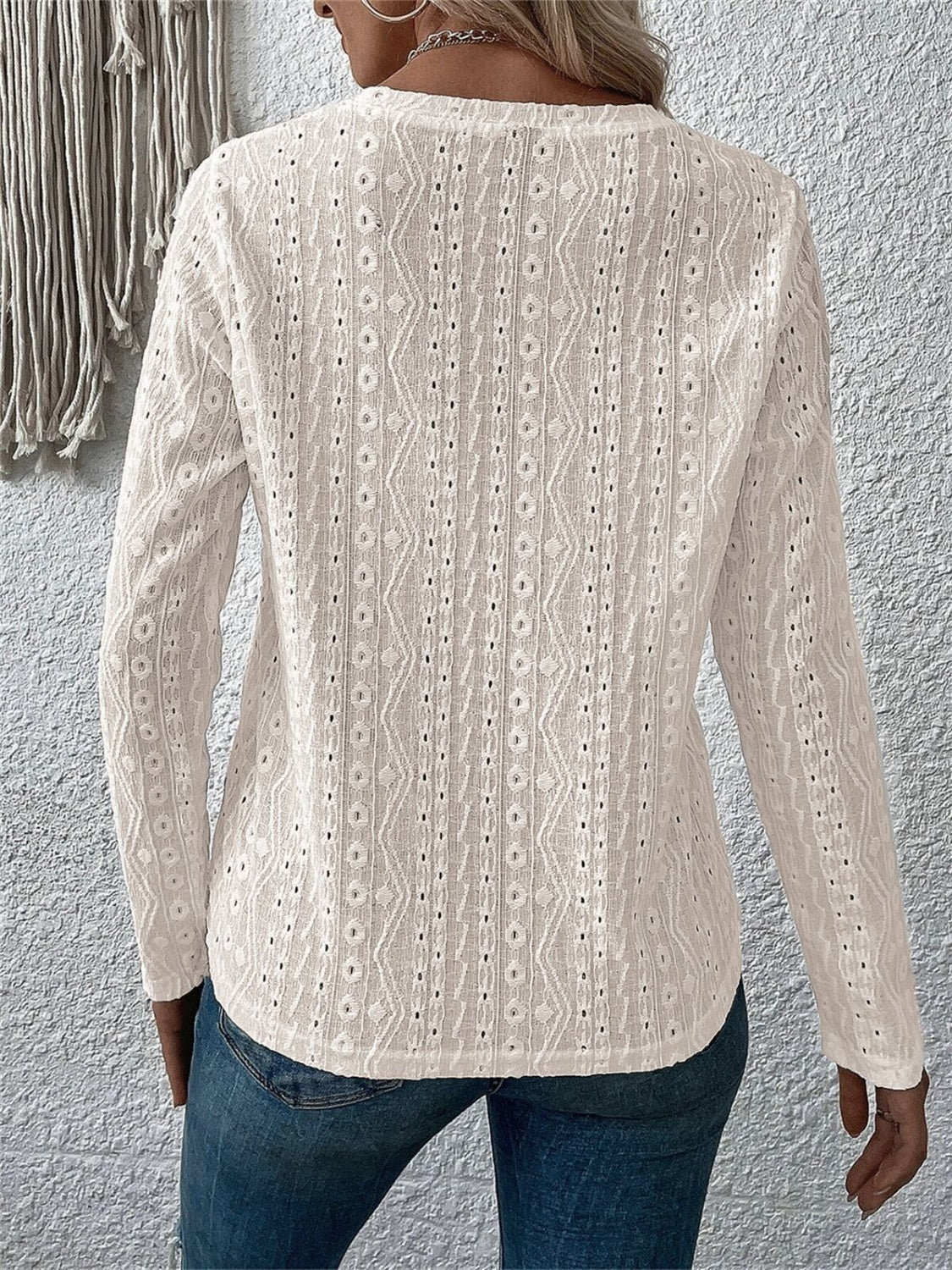 White long sleeve knit top with geometric eyelet pattern and v-neck.