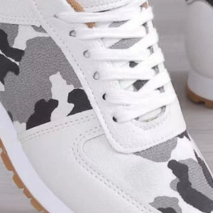 White sneakers with black and grey camouflage panels and white laces.