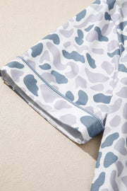 Camouflage print pajama set with blue trim on short sleeves and button-down shirt.