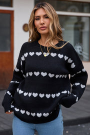 Black knit pullover sweater with white heart stripe pattern, crew neck, long sleeves.