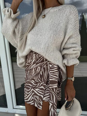 Cream voluminous sleeve knit sweater with ruffled cuffs, paired with a brown zebra print wrap skirt.