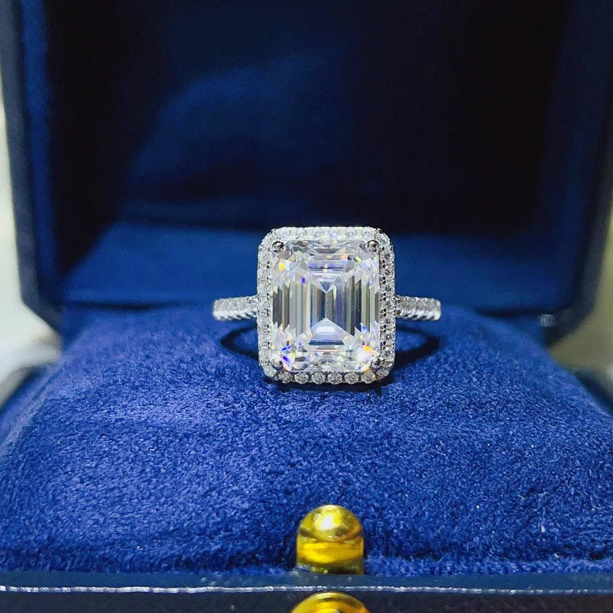 Emerald cut moissanite halo ring in sterling silver with pavé band.