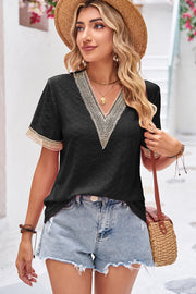 Black eyelet v-neck blouse with lace trim on neckline and sleeves.