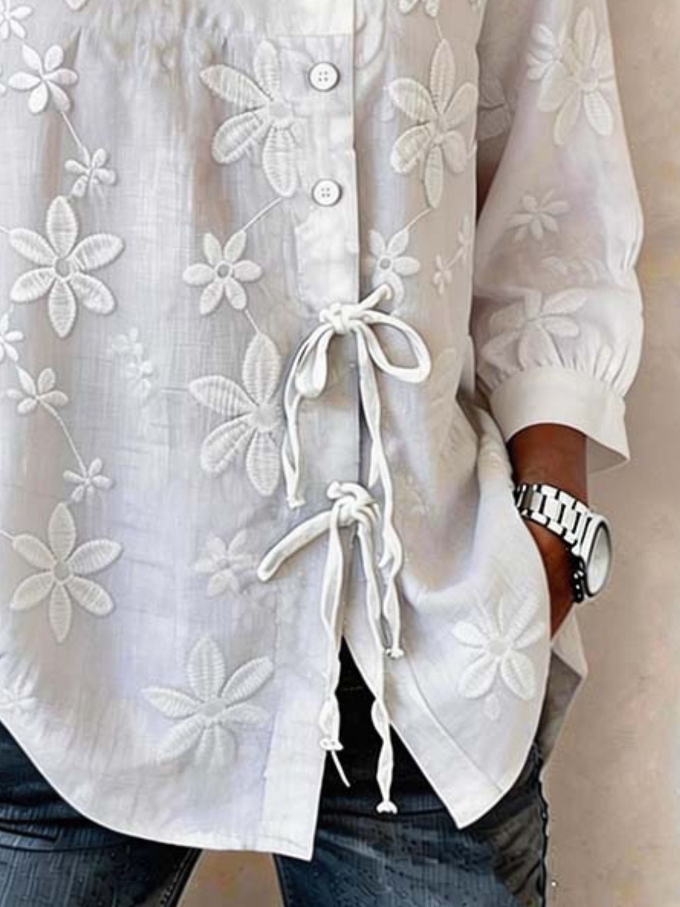 White embroidered floral button-down blouse with 3/4 sleeves and tie detail.