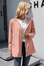 Blush pink hooded rain coat with white trim and zipper, casual lightweight jacket.