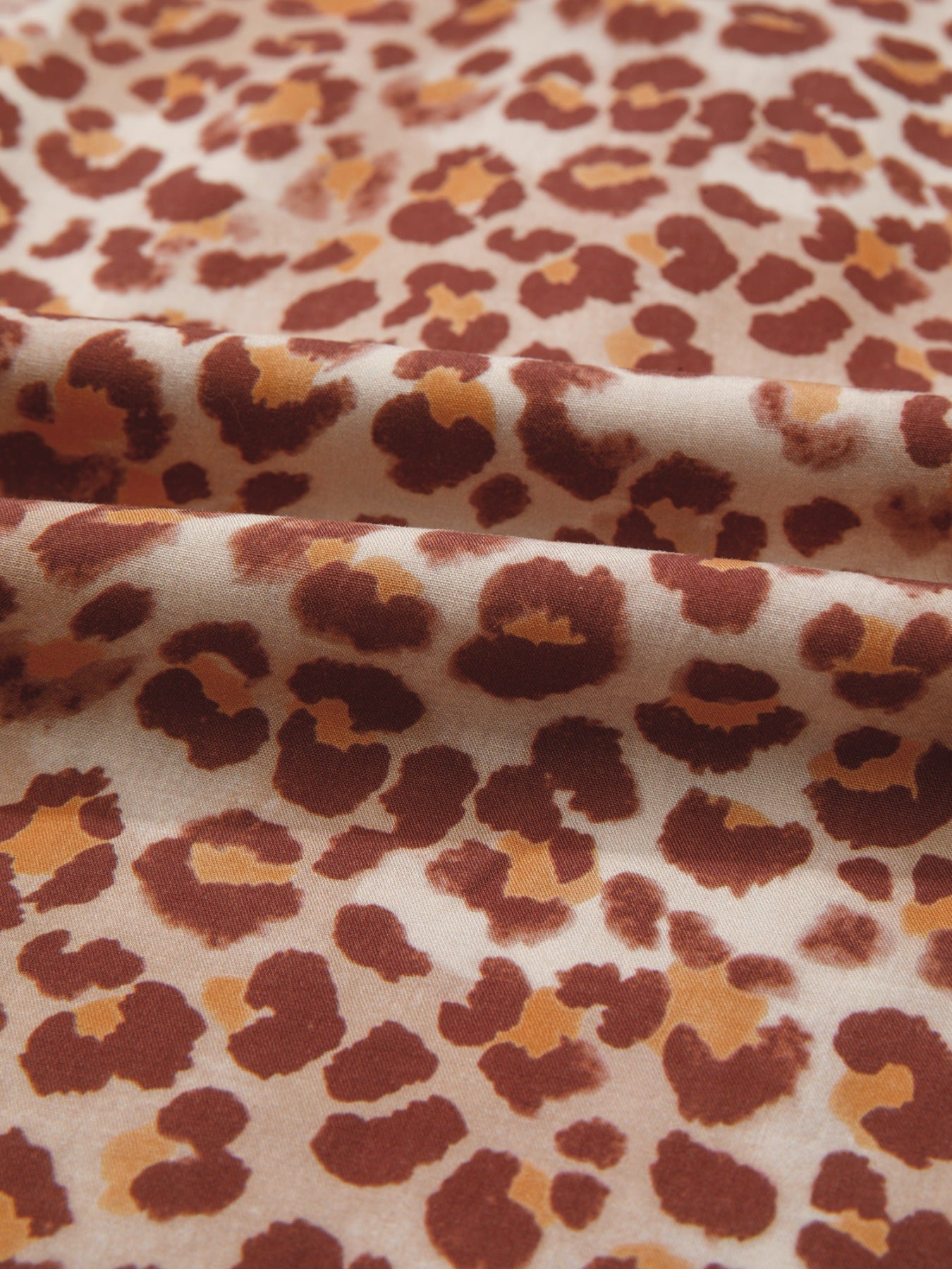 Smocked ruffled blouse with bold brown and tan animal print fabric.