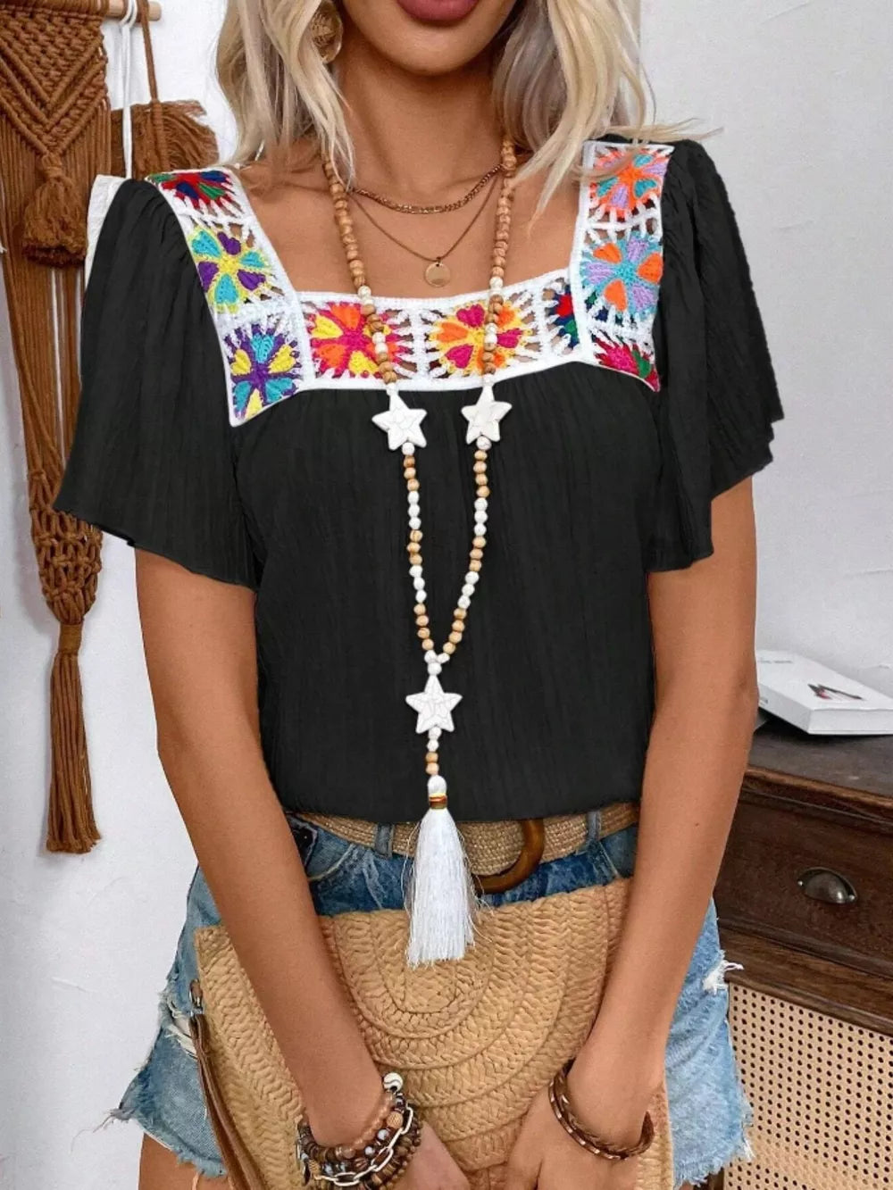Black square neck blouse with colorful embroidered yoke and flutter sleeves.